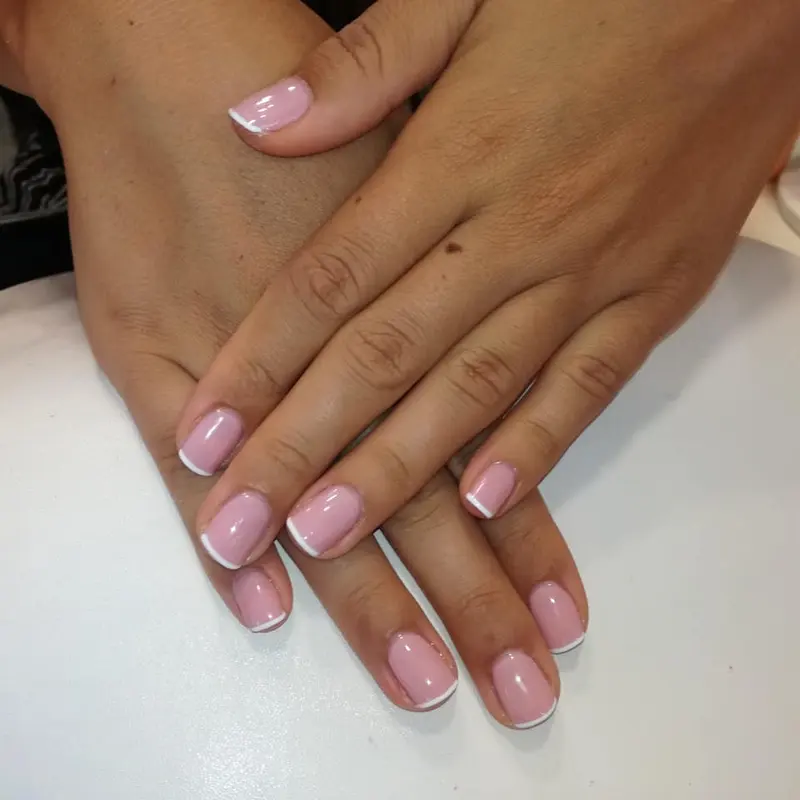 Two hands with a pink and white French manicure